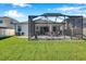 View of home's back patio, grill, and lush backyard with fencing at 2934 Living Coral Dr, Odessa, FL 33556