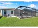 Landscaped backyard featuring a screened-in lanai with a patio set, perfect for outdoor relaxation at 2934 Living Coral Dr, Odessa, FL 33556