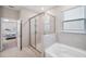 Bathroom featuring tiled shower with glass enclosure, soaking tub, and view into bedroom at 2934 Living Coral Dr, Odessa, FL 33556