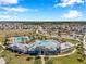 Aerial view of community pools, clubhouse, palm trees, landscaping, playground, and parking lot at 2934 Living Coral Dr, Odessa, FL 33556