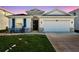 Charming home with stone accents, a two-car garage, and lush green lawn at dusk at 2934 Living Coral Dr, Odessa, FL 33556
