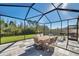 Spacious screened patio featuring outdoor dining set, stone tile, outdoor lighting, and backyard views at 2934 Living Coral Dr, Odessa, FL 33556