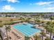 Aerial view of community pools, palm trees, landscaping, playground, and parking lot at 2934 Living Coral Dr, Odessa, FL 33556