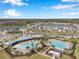 Aerial view of community pools with lounge chairs, palm trees, and covered patios at 2934 Living Coral Dr, Odessa, FL 33556