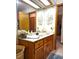 Bathroom vanity with wood cabinets, framed mirror, and wallpaper at 3050 Bayshore Dr, Spring Hill, FL 34608