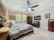Bright bedroom features a ceiling fan, large bed, decorative curtains, and a view of the outdoors at 32101 Goddard Dr, Wesley Chapel, FL 33543