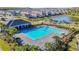 A high angle view of the community pool with lounge chairs, cabana, and landscaped grounds by a lake at 32779 Brooks Hawk Ln, Wesley Chapel, FL 33543