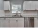Close-up of the stainless steel dishwasher, granite counters, and clean white cabinets at 3451 Pine St, Dunedin, FL 34698