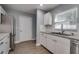 Modern kitchen with stainless fridge, white cabinets, granite counters, and stainless sink at 3451 Pine St, Dunedin, FL 34698