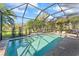 Beautiful pool area with a screened enclosure surrounded by palm trees and a well-maintained lawn at 4811 Forest Creek Trl, Parrish, FL 34219