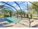 Gorgeous pool with shallow lounge area, waterfall feature, and screened enclosure surrounded by tropical plants at 4811 Forest Creek Trl, Parrish, FL 34219