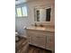 Bathroom view featuring a modern vanity with light granite countertop, window and wood-look floors at 500 New York Ave # 21, Dunedin, FL 34698