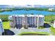 Aerial view of a seven-story condo building surrounded by lush landscaping and a serene waterfront at 6495 Shoreline Dr # 8105, Seminole, FL 33708