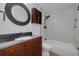 Bathroom features a vanity, dark countertop, round mirror, and a tub/shower combo with tiled walls at 6672 56Th N Ave, St Petersburg, FL 33709