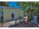 Backyard with charming yellow cottage, brick-lined pathway, and tropical plants at 805 Bruce Ave, Clearwater Beach, FL 33767