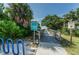 Inviting beach access with a wooden boardwalk surrounded by lush greenery and informative signage at 805 Bruce Ave, Clearwater Beach, FL 33767