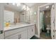 Bathroom featuring double vanity, white cabinets, and well-lit mirrors, and a shower with teal curtain at 8609 Winning Fields Rd, New Port Richey, FL 34655