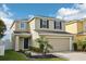 Two-story home with a neutral exterior, two-car garage, manicured landscaping, and a welcoming front entrance at 11301 Hudson Hills Ln, Riverview, FL 33579