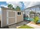 Outdoor shed and screened-in pool area with paved patio and tropical landscaping at 11301 Hudson Hills Ln, Riverview, FL 33579