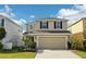 Two-story home featuring a two-car garage, neutral paint, black shutters, and tasteful landscaping at 11301 Hudson Hills Ln, Riverview, FL 33579