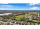 Panoramic aerial view of homes in a lush neighborhood bordering an open green field and blue sky at 11822 Crawford Parrish Ln, Parrish, FL 34219