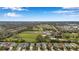 Aerial view showcasing homes near an open field with mature landscaping and blue skies at 11822 Crawford Parrish Ln, Parrish, FL 34219