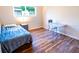Bedroom featuring wood flooring, desk, chair, bed with gray blanket and window views at 13116 Sheridan Dr, Hudson, FL 34667