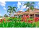 Scenic exterior view of the clubhouse with lush greenery and vibrant red plants, overlooking the well-maintained golf course at 13823 Messina Loop # 204, Bradenton, FL 34211