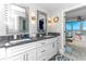 Modern bathroom featuring double vanity, granite counters, and unique mirror designs with views to the Primary bedroom and water beyond at 1390 Gulf Blvd # Ph 2, Clearwater Beach, FL 33767