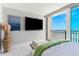 This bedroom features a flat-screen TV and sliding glass doors leading to a private balcony overlooking the ocean at 1390 Gulf Blvd # Ph 2, Clearwater Beach, FL 33767