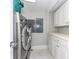 Well-lit laundry room with stainless steel washer and dryer, and ample storage cabinets at 1390 Gulf Blvd # Ph 2, Clearwater Beach, FL 33767