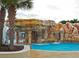 Inviting pool area with a waterfall feature, palm trees, and lush landscaping for a tropical paradise at 16313 Bridgecrossing Dr, Lithia, FL 33547