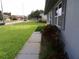A sidewalk on the side of the house is surrounded by green grass and landscaping shrubs and plants at 1660 Caledonia Dr, Palm Harbor, FL 34684