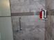 Shower with grey marble tile, shampoo products, and grey mosaic border at 1660 Caledonia Dr, Palm Harbor, FL 34684