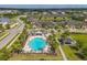 Aerial view showcasing a community pool surrounded by palm trees and nearby residential buildings at 1706 Trailwater St, Ruskin, FL 33570