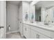 Bright bathroom features a dual sink vanity with white cabinetry and a walk-in shower with a glass door at 19398 Great Intention Way, Lutz, FL 33558