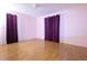 Bright bedroom with hardwood floors, light pink walls, and large windows dressed with decorative dark purple curtains at 2118 Ne Coachman Rd, Clearwater, FL 33765