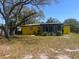 Charming single-story home with a bright yellow exterior and well-kept front yard at 2118 Ne Coachman Rd, Clearwater, FL 33765
