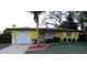 Charming single-story home featuring a bright yellow exterior, well-maintained landscaping, and an attached one-car garage at 2118 Ne Coachman Rd, Clearwater, FL 33765