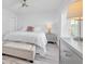 Bright bedroom with a white bed, gray dresser, bench seat and wood look floors at 2700 Bayshore Blvd # 588, Dunedin, FL 34698