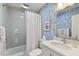 Charming bathroom featuring unique blue wallpaper, white vanity, and shower-tub combination at 3006 W Angeles St, Tampa, FL 33629