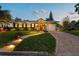 Well-lit home showcasing an inviting front yard, brick walkway, manicured hedges, and attached garage at 3006 W Angeles St, Tampa, FL 33629
