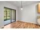 An open dining area has wood floors, glass sliding door, and a decorative light fixture at 30103 Mossbank Dr, Wesley Chapel, FL 33543