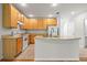 Kitchen with white appliances, light wood cabinets and island with sink at 30103 Mossbank Dr, Wesley Chapel, FL 33543