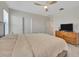 Bright primary bedroom with ceiling fan, carpet flooring and dresser with television at 5758 Hollingworth Trl, Wesley Chapel, FL 33545
