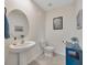 Stylish powder room with pedestal sink, round mirror and decorative wall art at 5758 Hollingworth Trl, Wesley Chapel, FL 33545