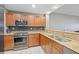 Well-lit kitchen with stainless steel oven and microwave, granite countertops, wood cabinets, and tiled floor at 628 Cleveland St # 1208, Clearwater, FL 33755