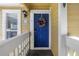 Inviting blue front door with wreath, number 310, and white railing, set against yellow siding at 115 112Th Ne Ave # 310, St Petersburg, FL 33716