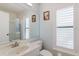 Bright bathroom with glass shower door, white vanity, and plantation shutters at 11521 Rose Tree Dr, New Port Richey, FL 34654