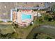 Aerial view of a beautiful outdoor swimming pool area with plenty of lounge chairs and a nearby pond at 11521 Rose Tree Dr, New Port Richey, FL 34654
